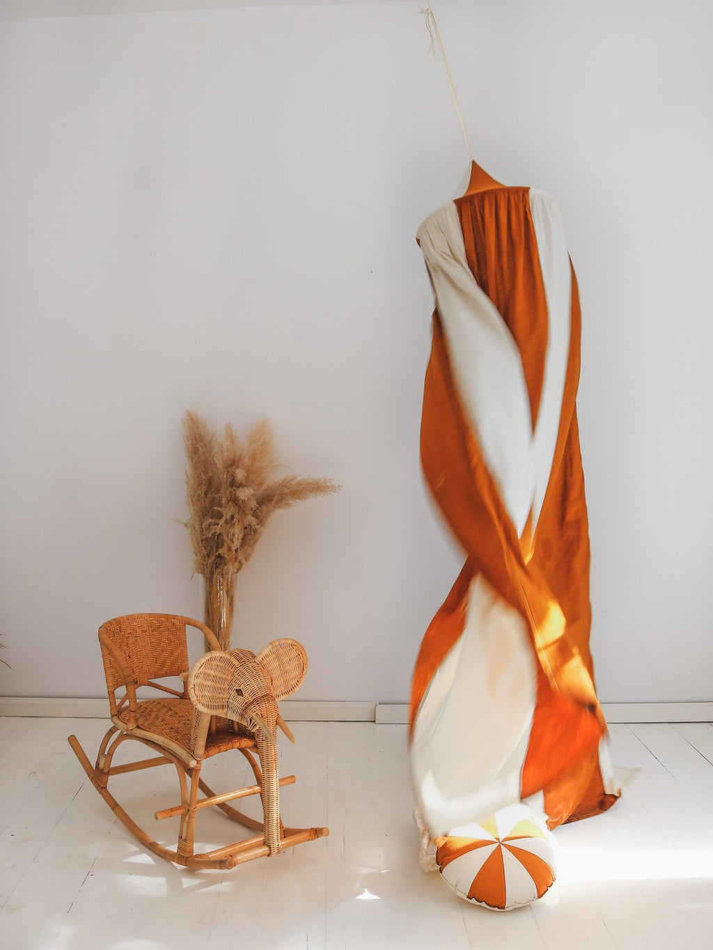 11. Caramel and cream canopy twisted and hanging next to a wicker chair