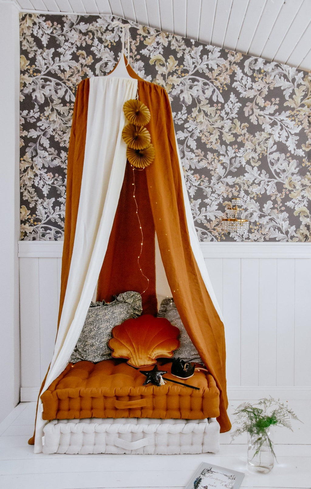 4. Caramel and cream canopy over a bed with cushions and floral wallpaper background