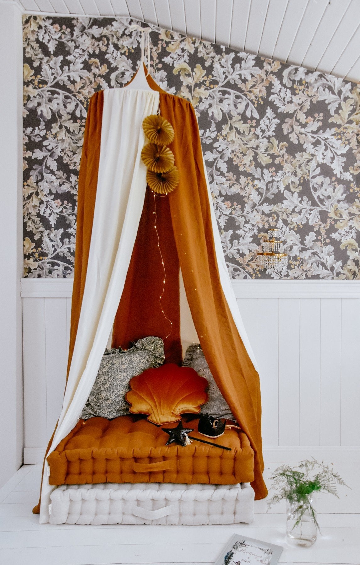 4. Caramel and cream canopy over a bed with cushions and floral wallpaper background
