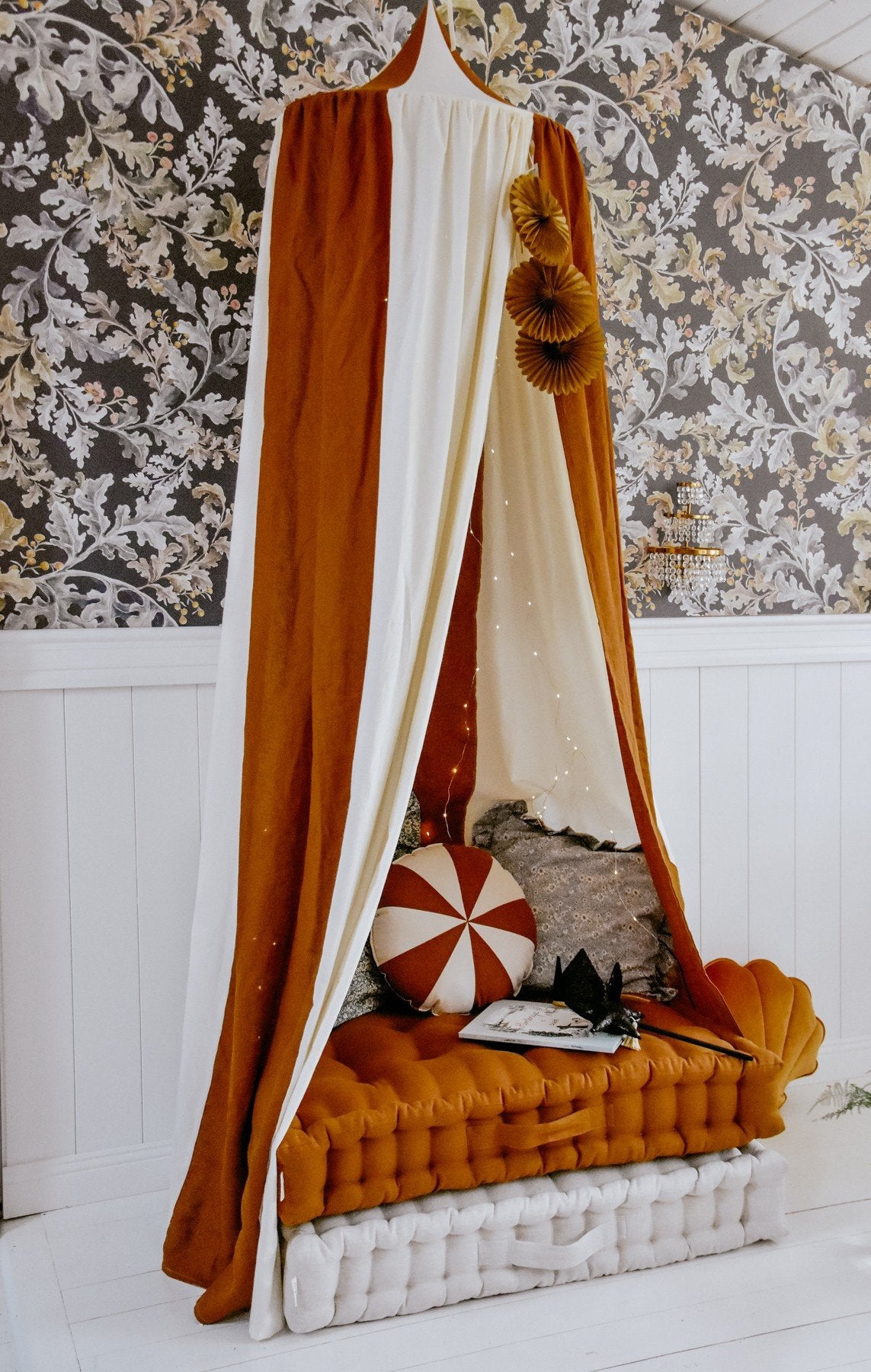 15. Caramel and cream canopy over a bed with decorative pillows and floral wallpaper