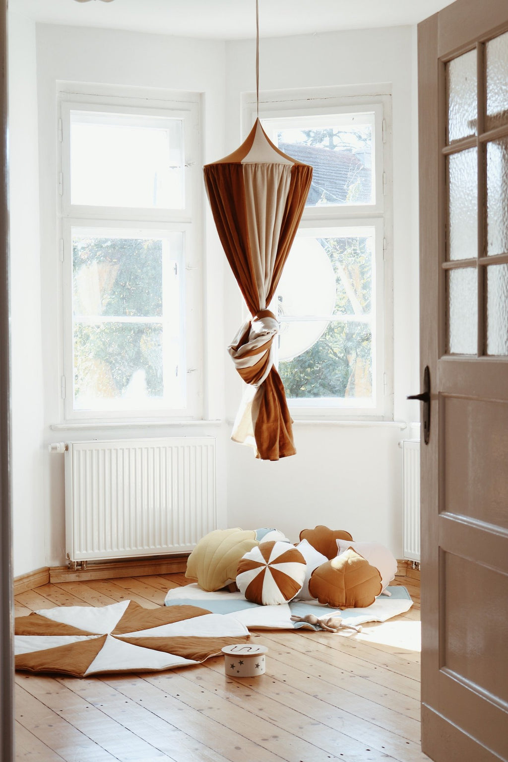 6. Caramel and cream canopy hanging in a sunlit room with cushions and wooden floor