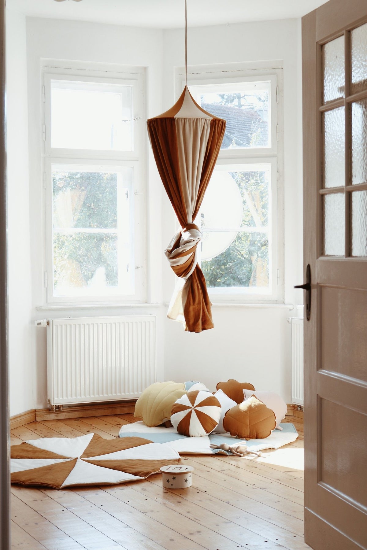 6. Caramel and cream canopy hanging in a sunlit room with cushions and wooden floor