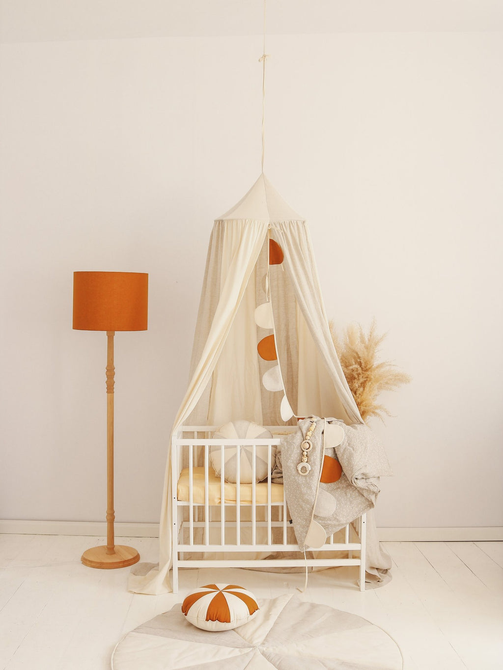 10. Cream canopy with orange accents over crib in a cozy nursery