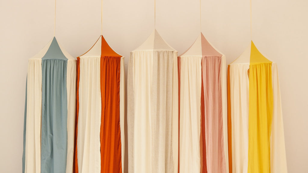 5. Five canopies in cream, blue, orange, pink, and yellow hanging in a row