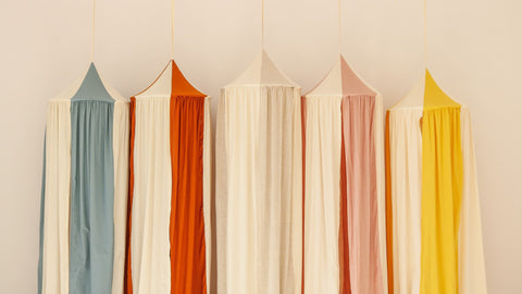 5. Five canopies in cream, blue, orange, pink, and yellow hanging in a row