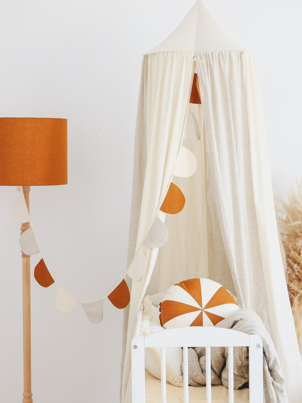 3. Cream canopy with orange and white cushion and garland in a nursery