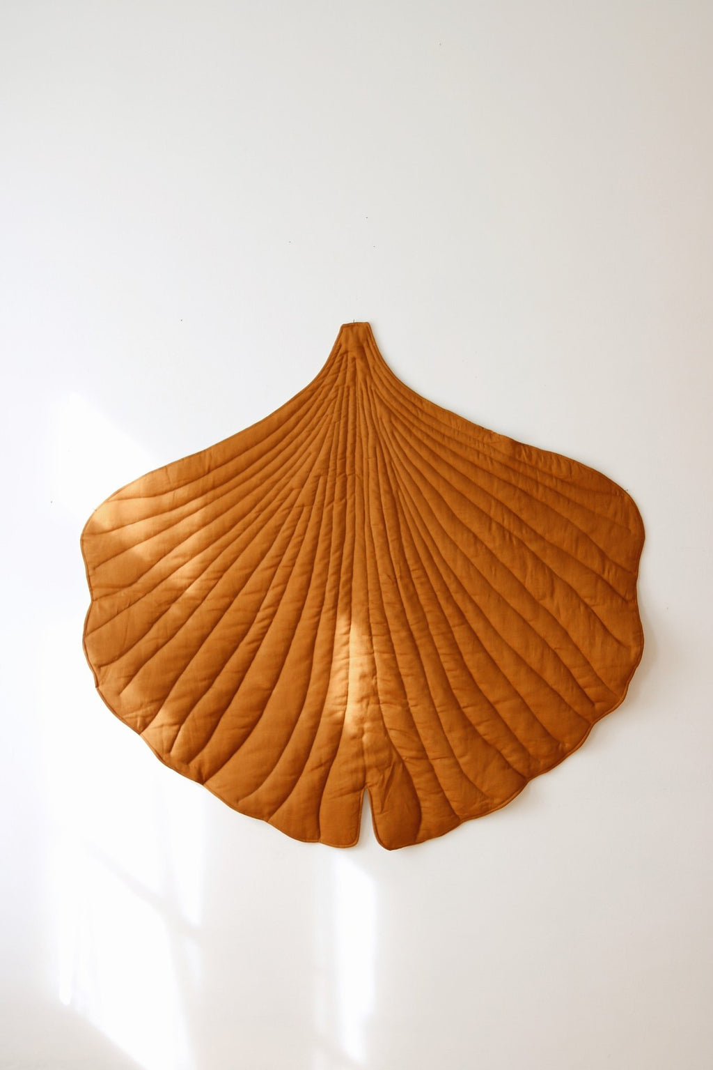 1. Caramel ginkgo leaf playmat displayed on a wall in a bright room, emphasizing its decorative appeal