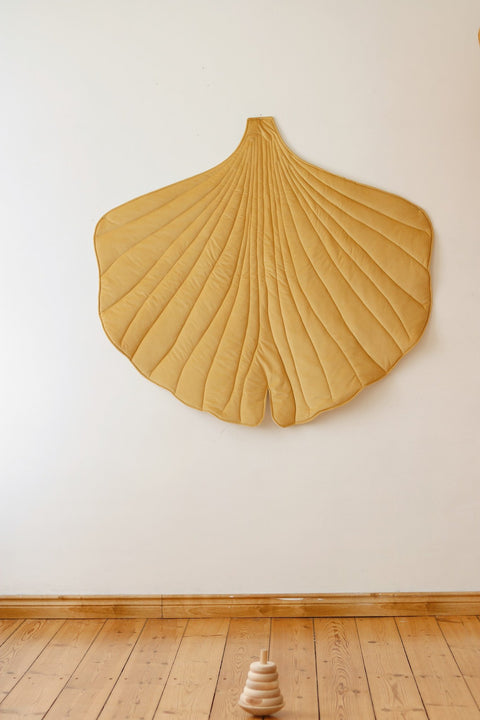2. Yellow ginkgo leaf playmat displayed on a wooden floor against a white wall