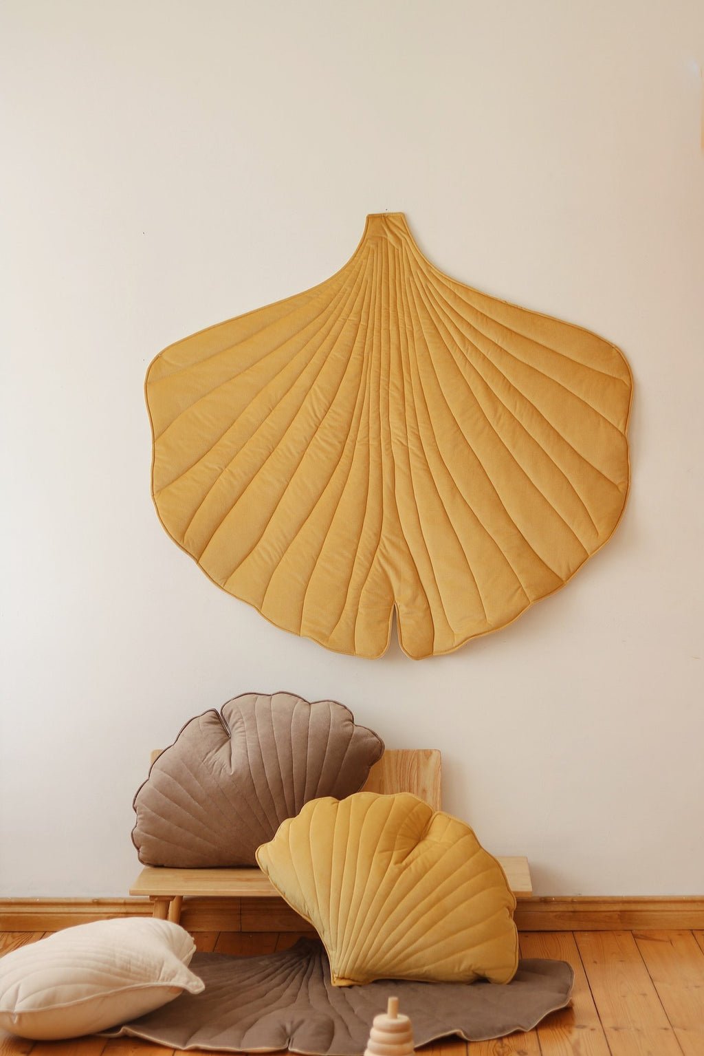 3. Yellow ginkgo leaf playmat on wall with matching cushions on wooden floor