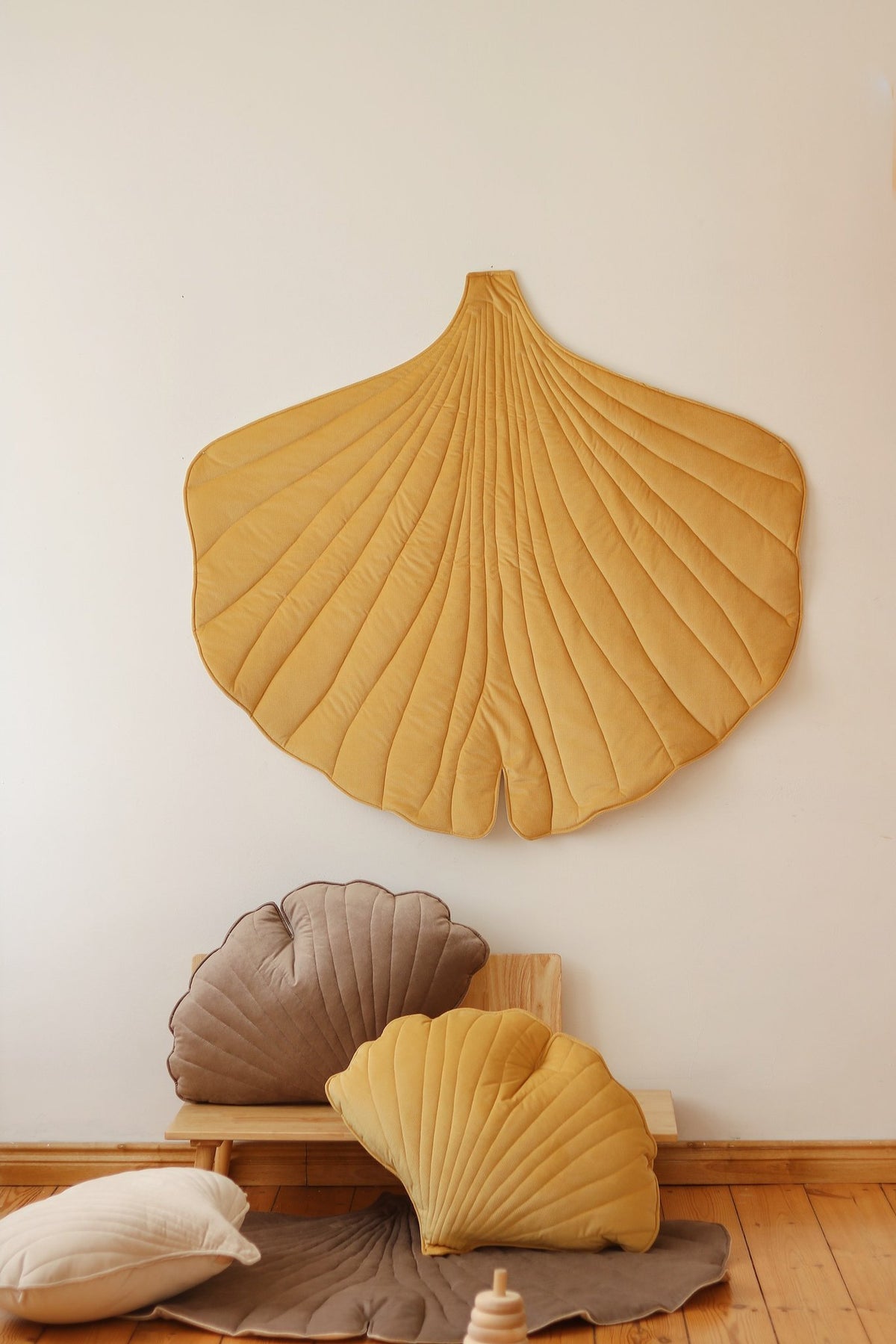 3. Yellow ginkgo leaf playmat on wall with matching cushions on wooden floor