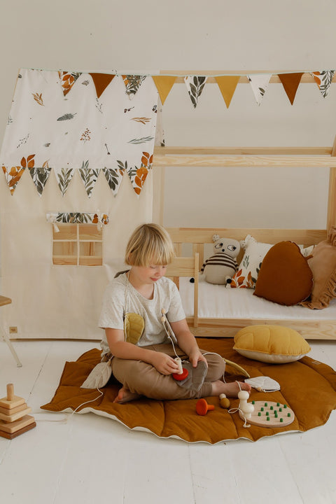 1. Child playing with toys on caramel leaf playmat in a wooden playhouse