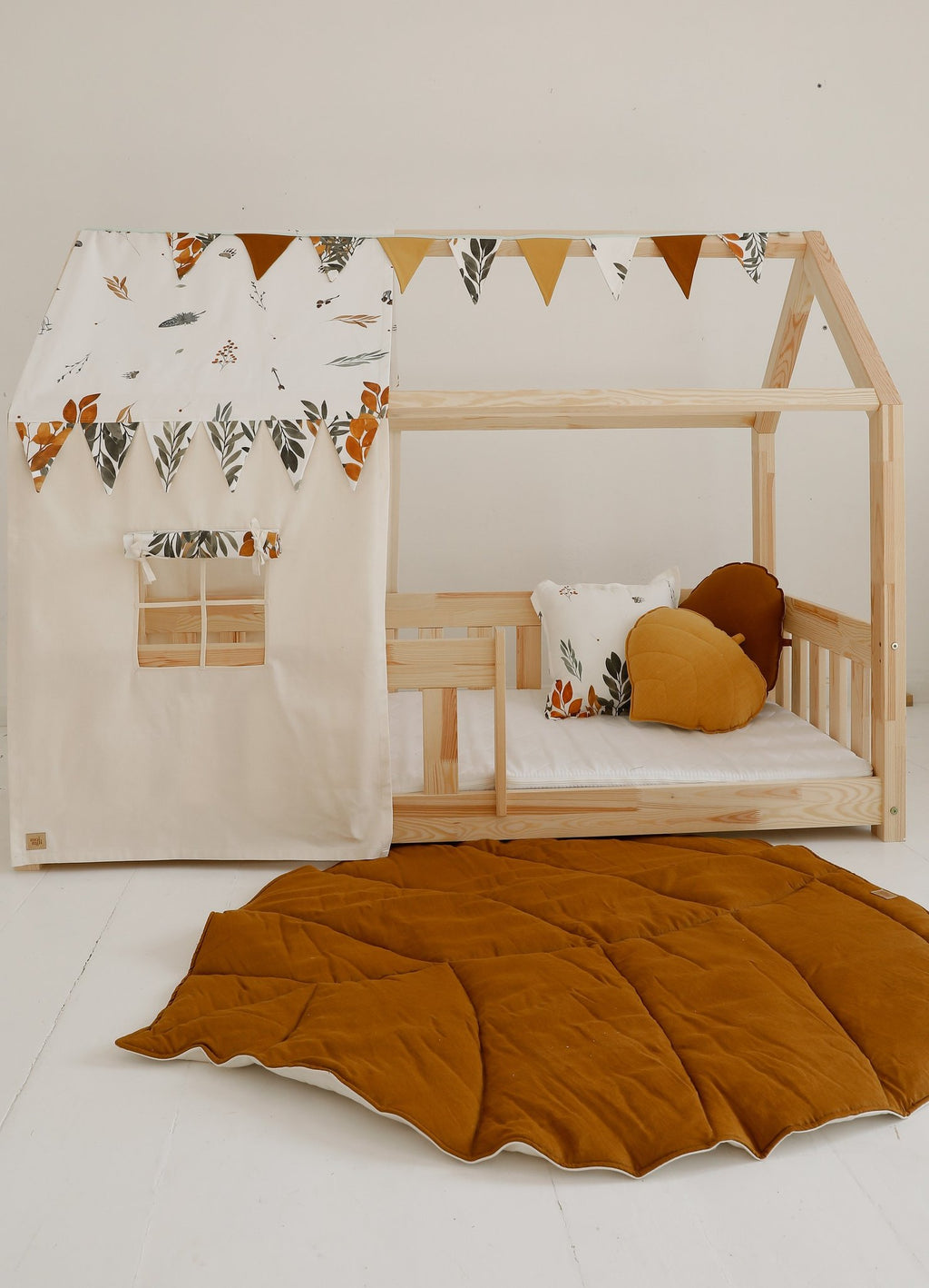1. Wooden playhouse with caramel leaf playmat on the floor, decorated with bunting and cushions