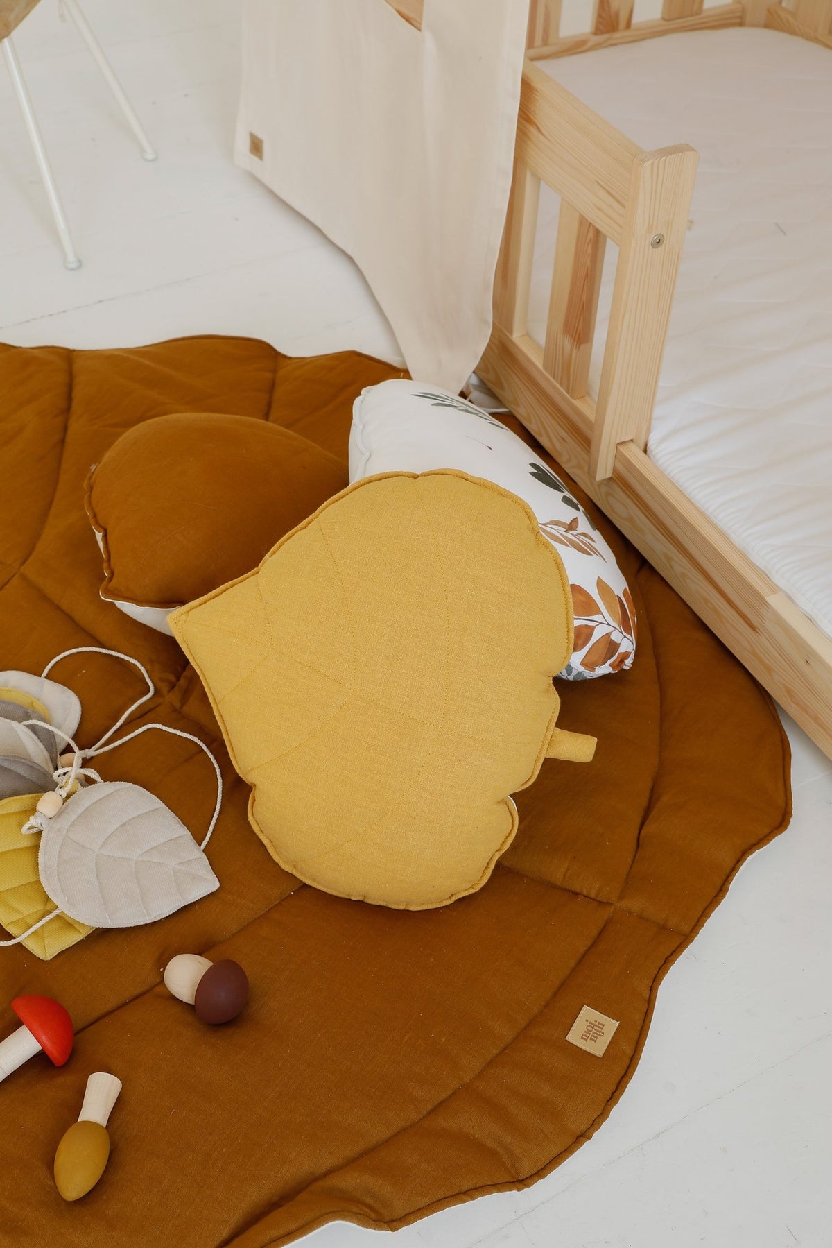 3. Detail of caramel leaf playmat with yellow cushion and toys in a toddler's room
