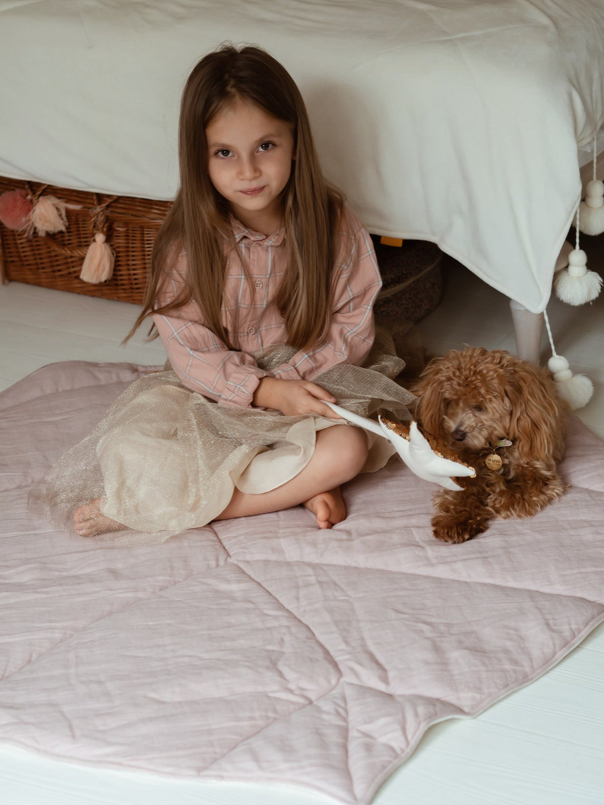 1. Girl sitting on powder pink leaf playmat with a small dog in a bedroom
