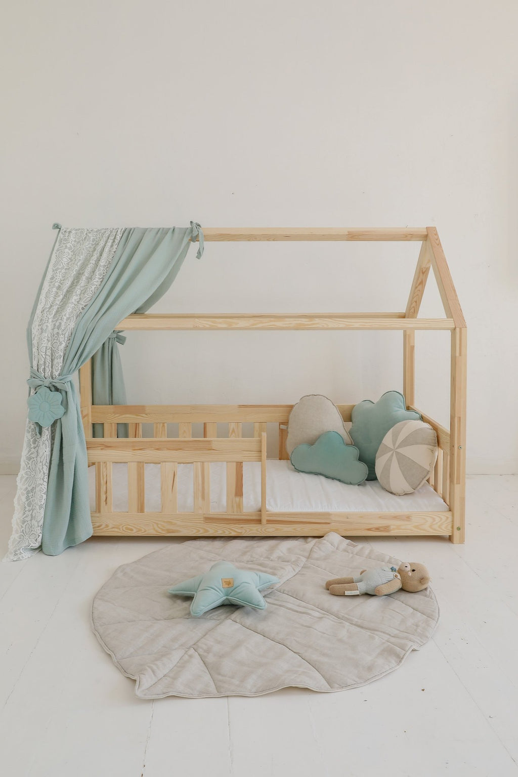 3. Sand leaf playmat in nursery with wooden bed, blue curtains, and plush toys