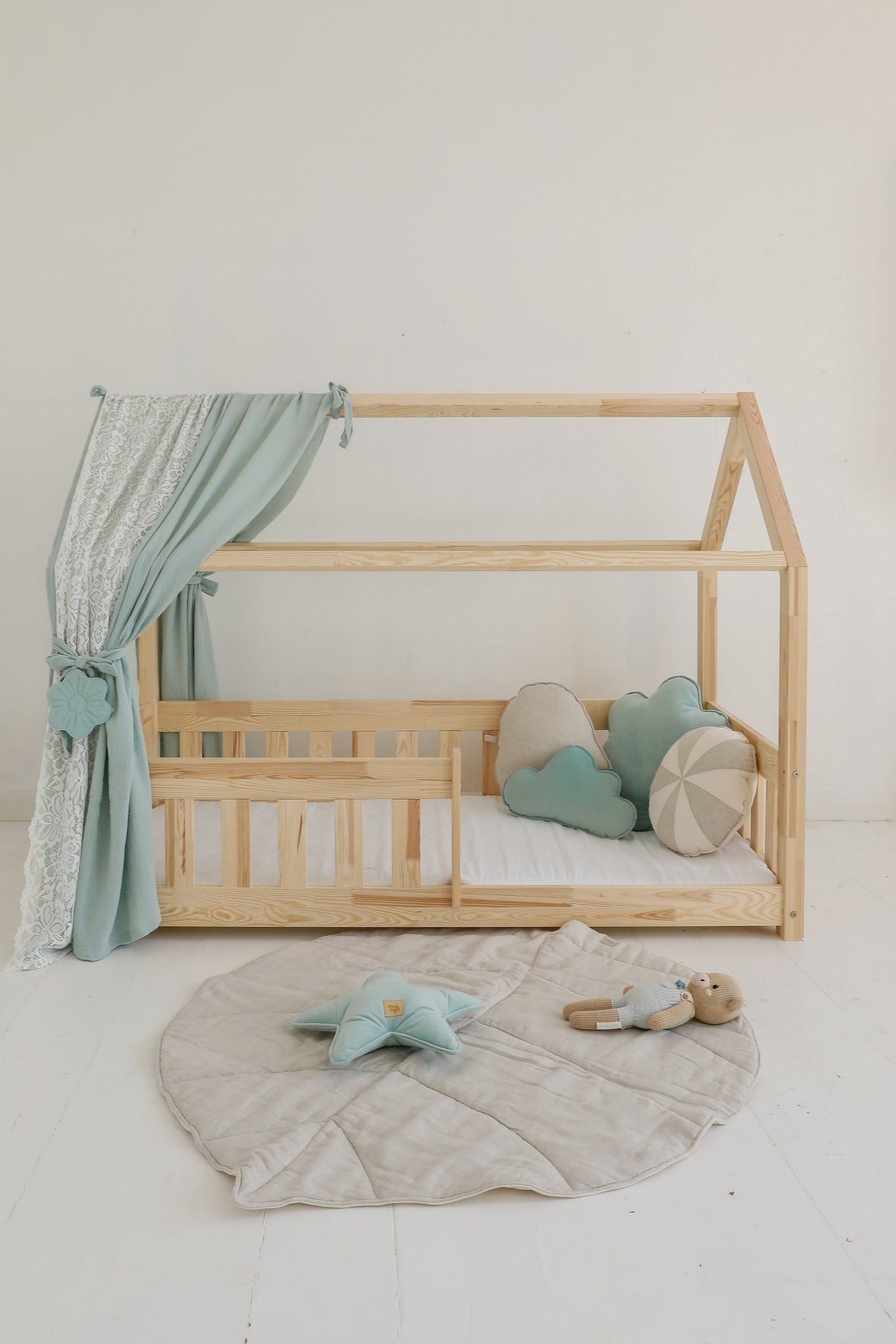 3. Sand leaf playmat in nursery with wooden bed, blue curtains, and plush toys