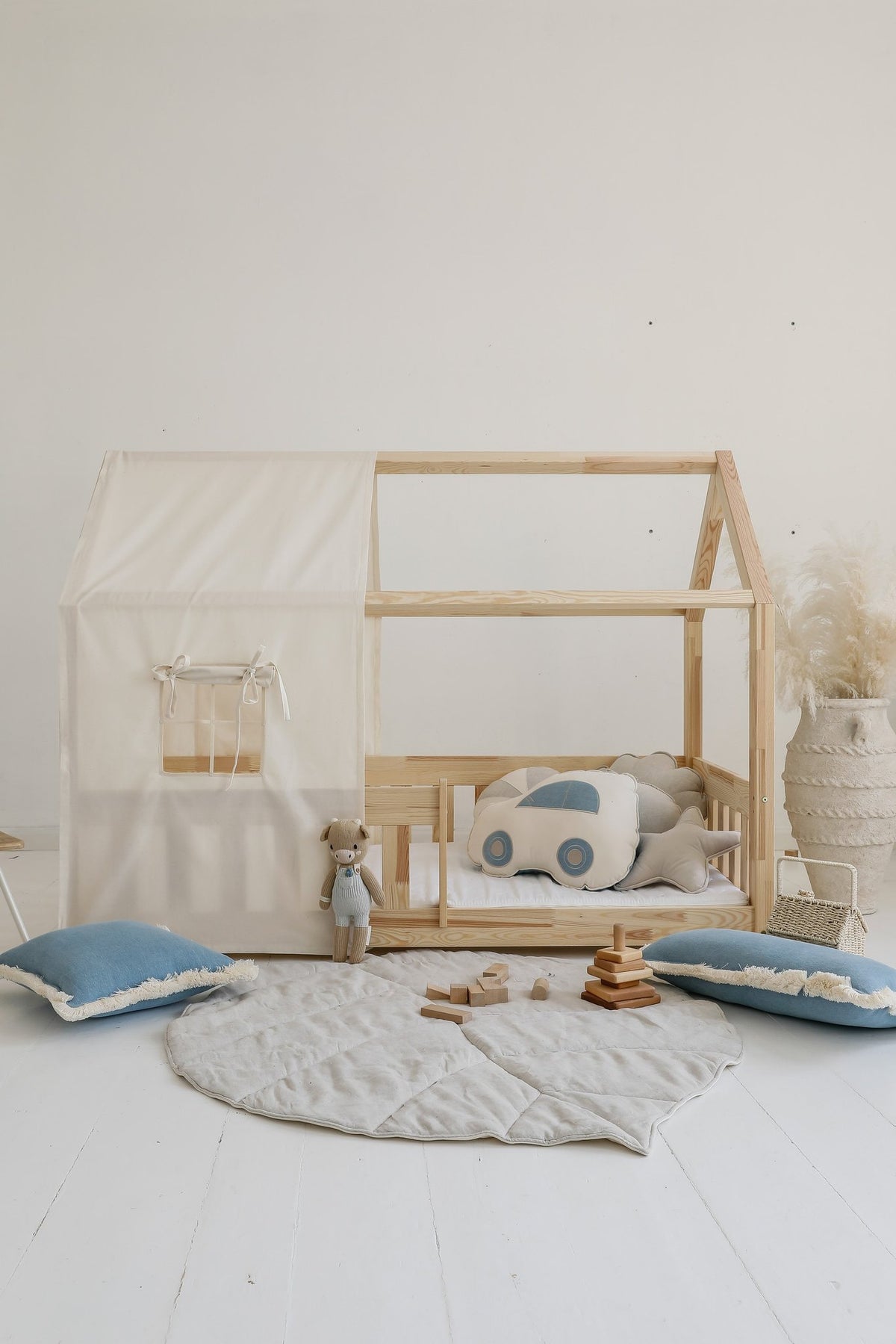 4. Sand playmat in children's room with wooden bed, car pillow, and blue cushions