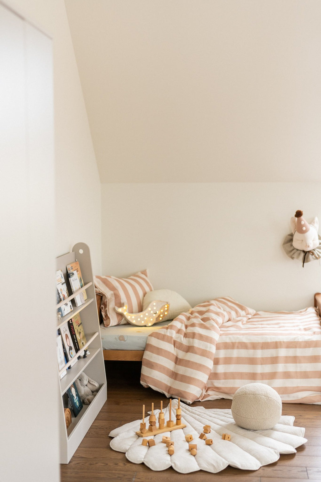 1. Organic cotton and linen shell playmat in sand color in a child's bedroom with striped bedding and toys