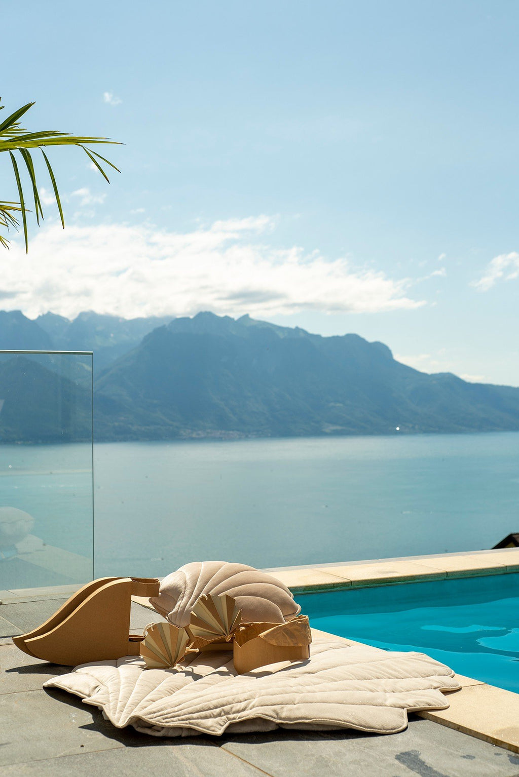 5. Child playing on beige ginkgo leaf-shaped playmat by poolside with mountain view
