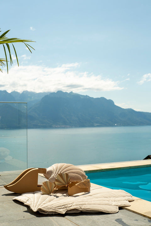 5. Child playing on beige ginkgo leaf-shaped playmat by poolside with mountain view