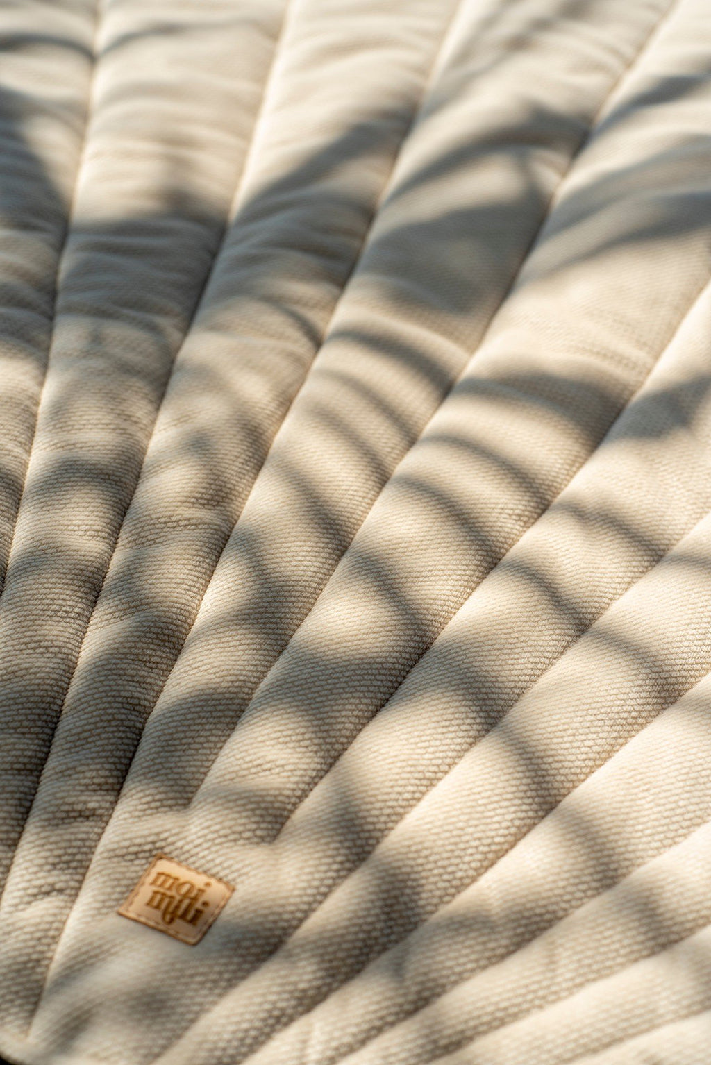 9. Close-up of beige ginkgo leaf-shaped playmat with shadows and logo detail