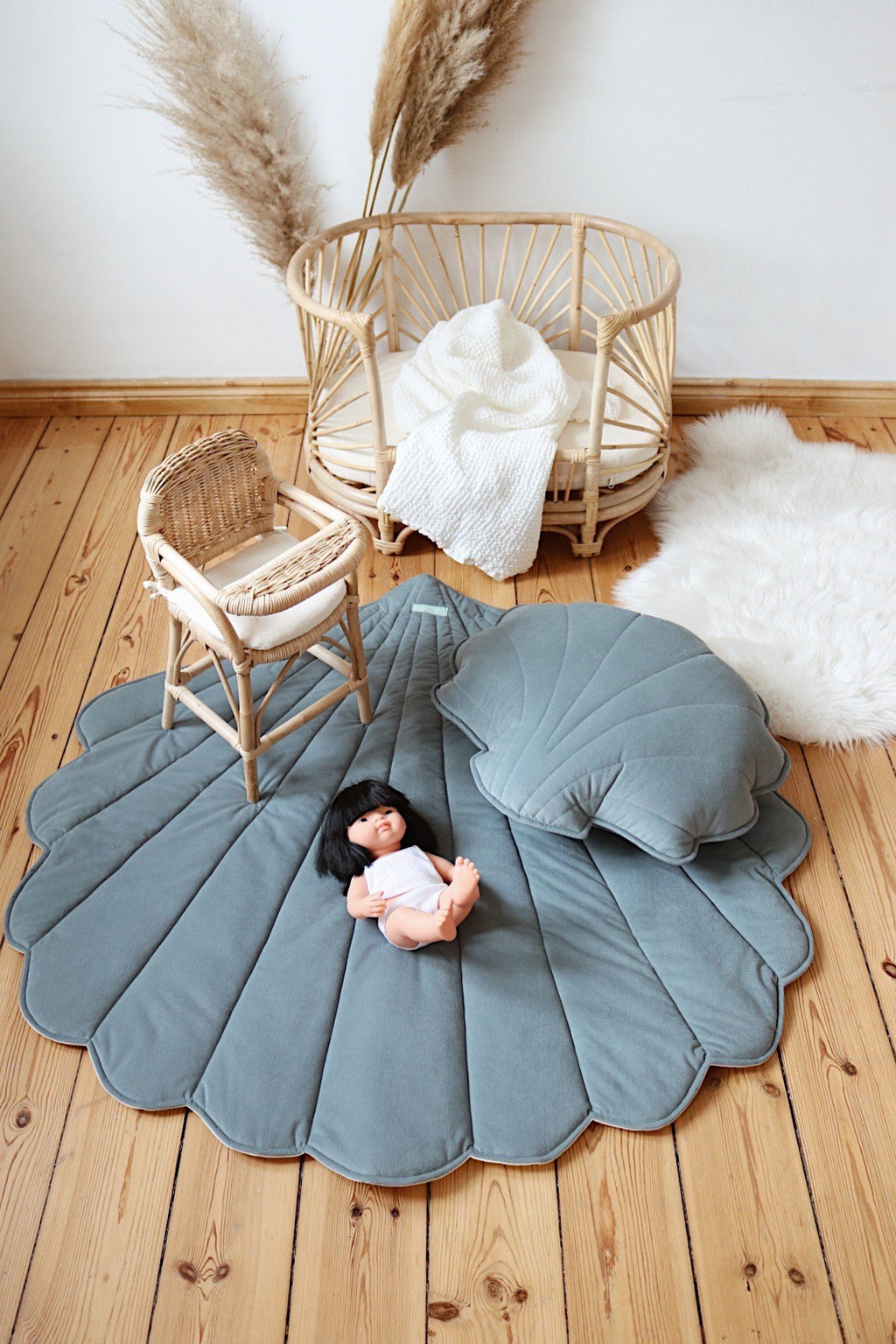 2. Blue shell-shaped playmat with wicker furniture and doll in cozy room setting, perfect for toddler's play area