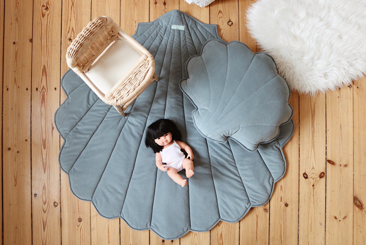 1. Blue ginkgo leaf-shaped playmat on wooden floor with wicker chair and doll, ideal for children's room or play area