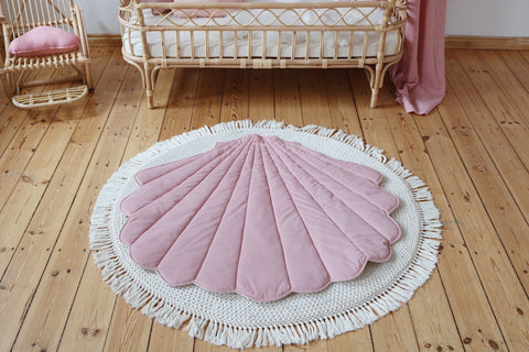 4. Powder pink shell playmat on woven rug in front of rattan crib with pink canopy