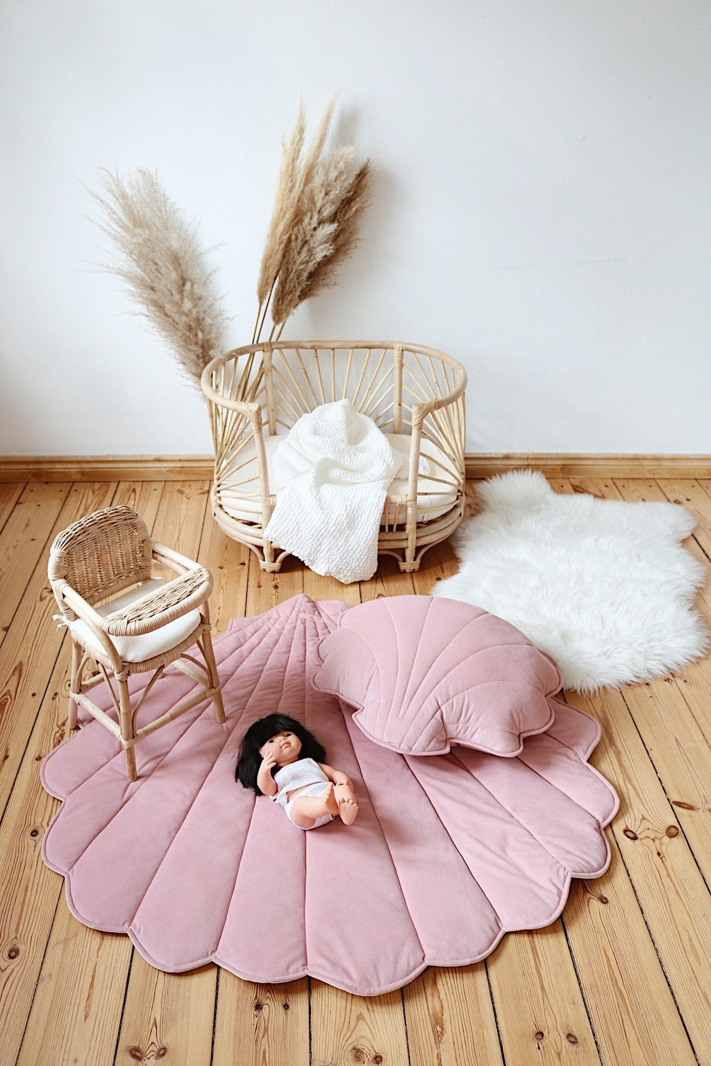 5. Powder pink shell playmat with matching pillow and doll in nursery setting
