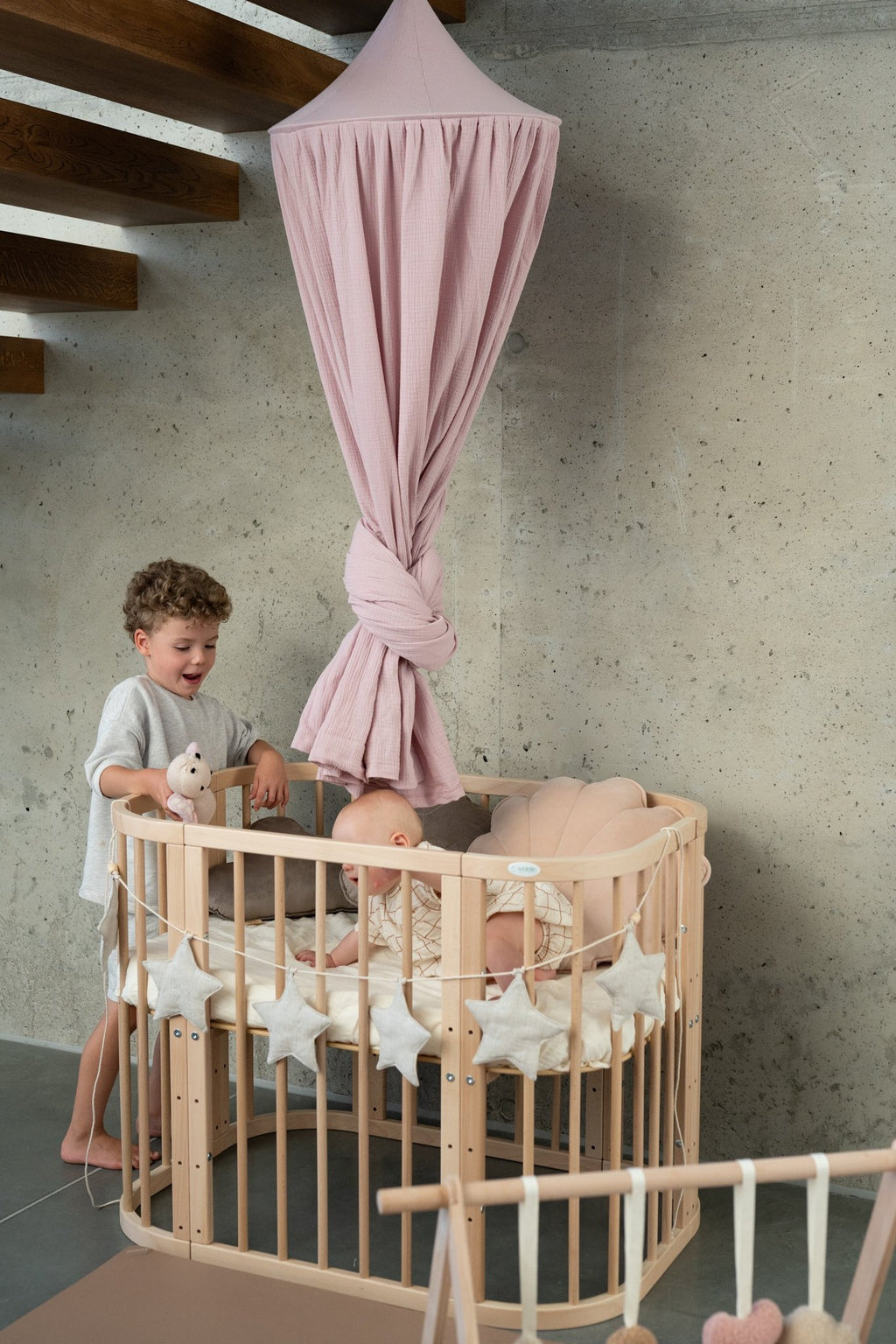 5. Two children playing near crib with pink canopy and star garland