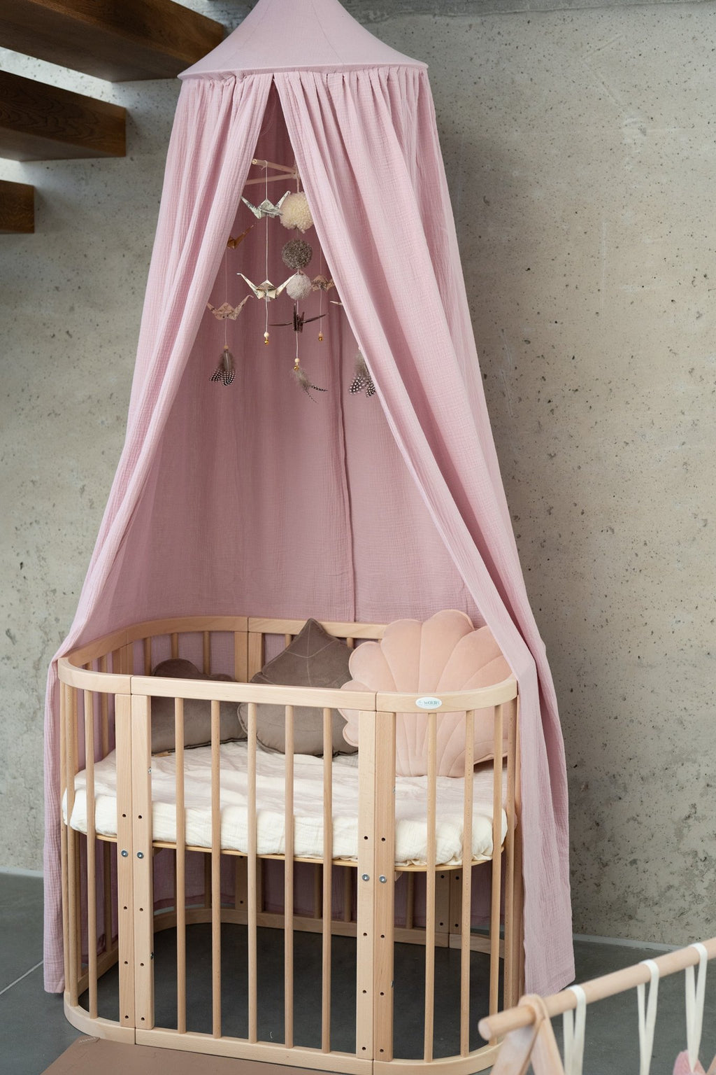1. Baby crib with pink organic cotton canopy in a modern nursery setting