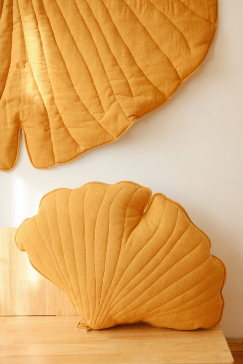 3. Close-up of mango-colored ginkgo leaf cushion and playmat on wooden bench