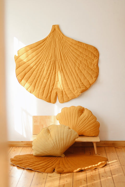 1. Mango-colored ginkgo leaf playmat and cushions in a sunlit room with wooden floor