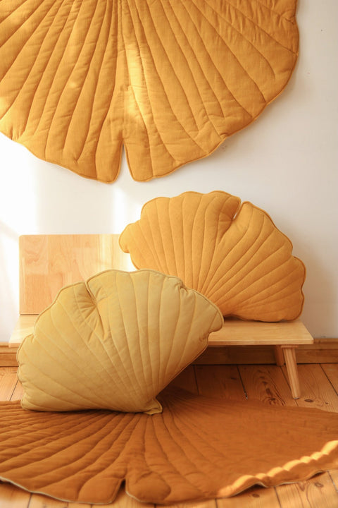 1. Room setting with mango-colored ginkgo leaf playmat and matching cushions on wooden floor