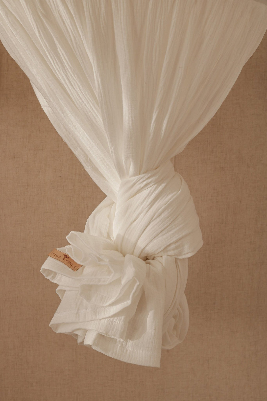 3. Close-up of cream cotton canopy fabric tied with a decorative knot, showcasing texture and label