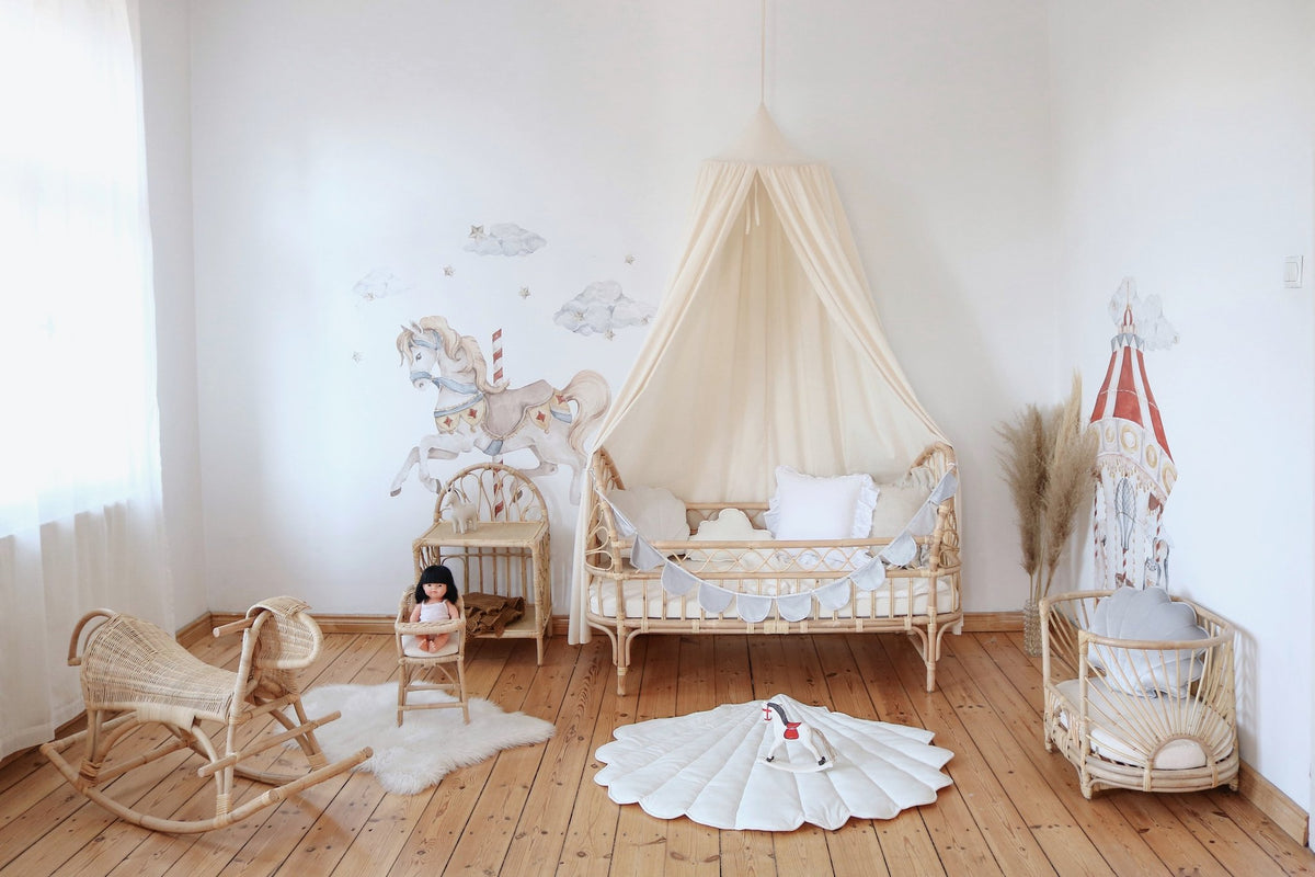 7. Playroom with organic cotton canopy, rattan crib, and carousel-themed decor