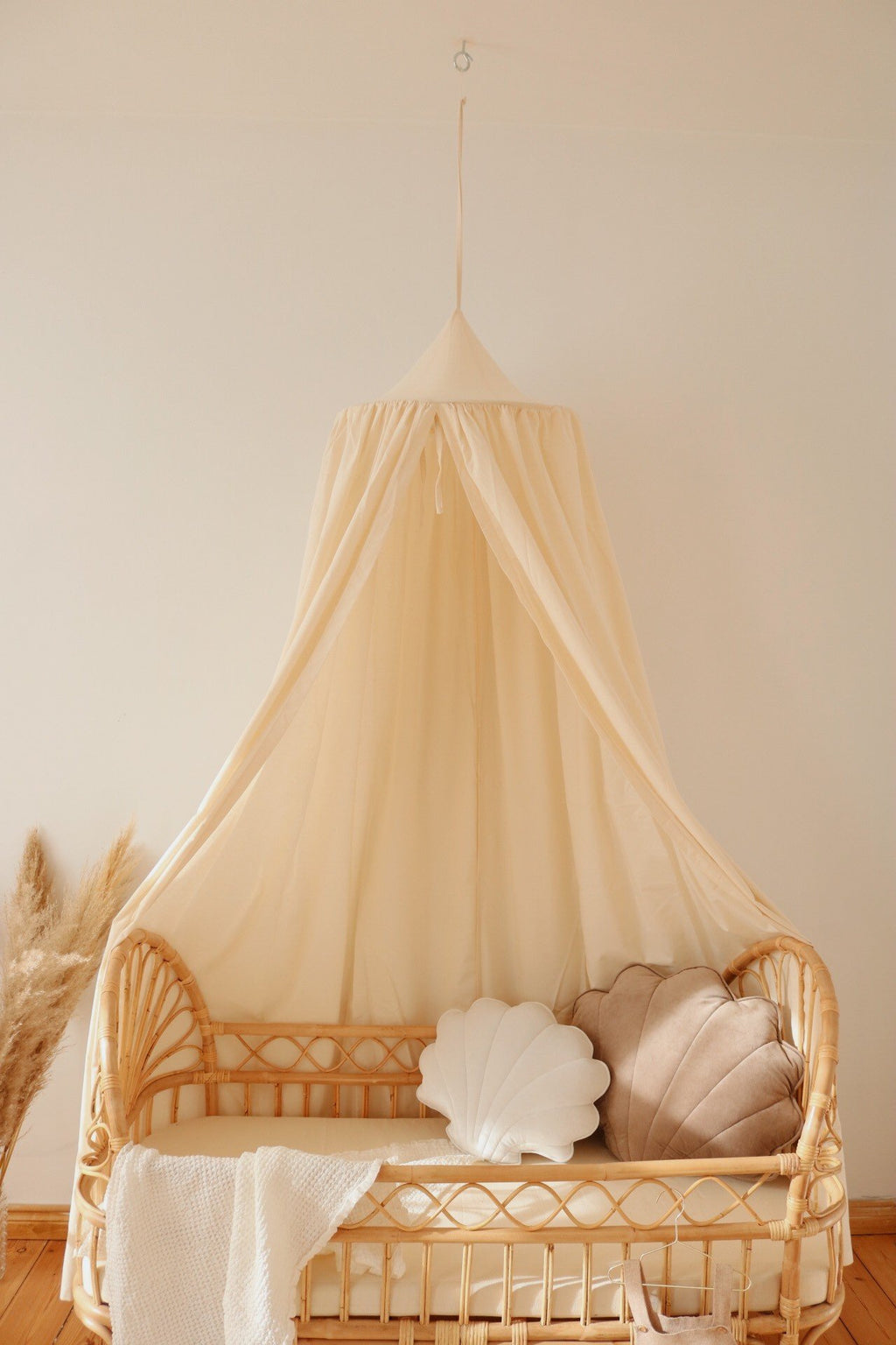 4. Organic cotton canopy over rattan crib with shell-shaped cushions in cozy nursery