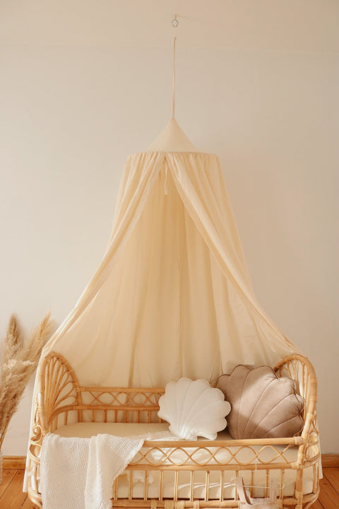 4. Organic cotton canopy over rattan crib with shell-shaped cushions in cozy nursery