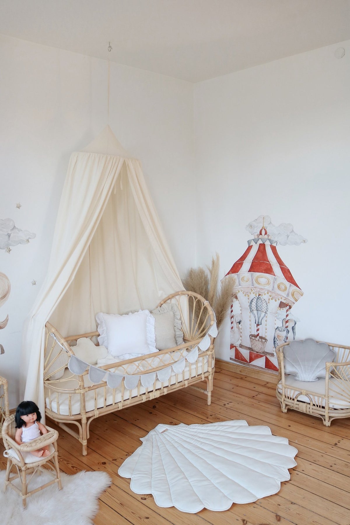6. Nursery with organic cotton canopy over crib, featuring carousel wall art and rattan furniture