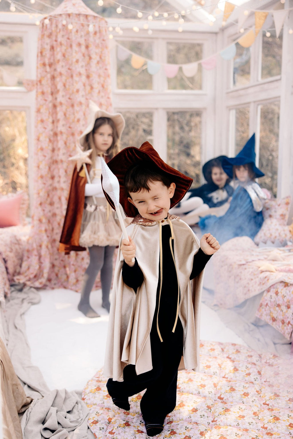 6. Three children in costumes playing near floral canopy in a bright room