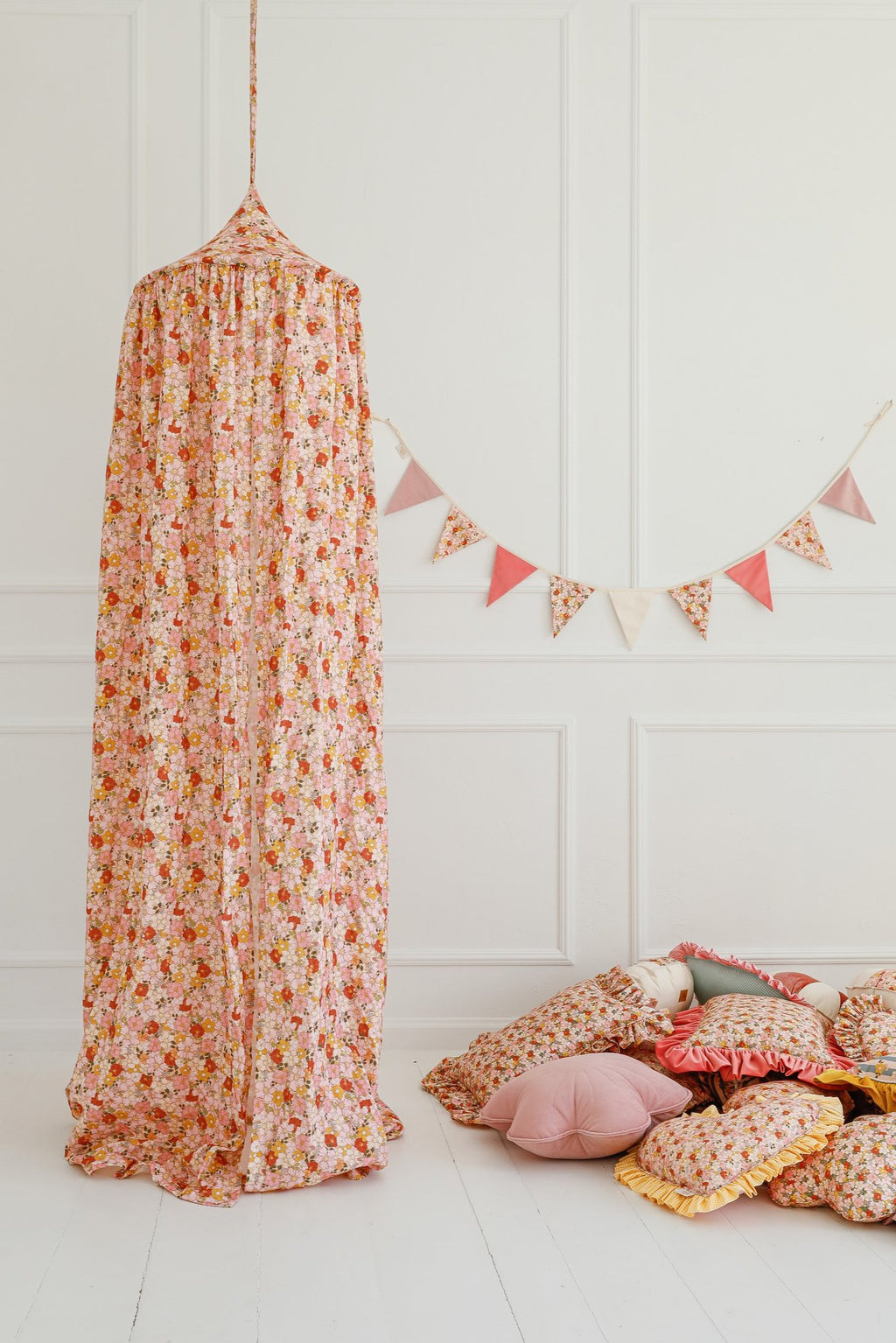 2. Floral canopy in pink and orange with matching cushions and garland in a bright room