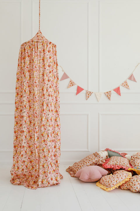 2. Floral canopy in pink and orange with matching cushions and garland in a bright room