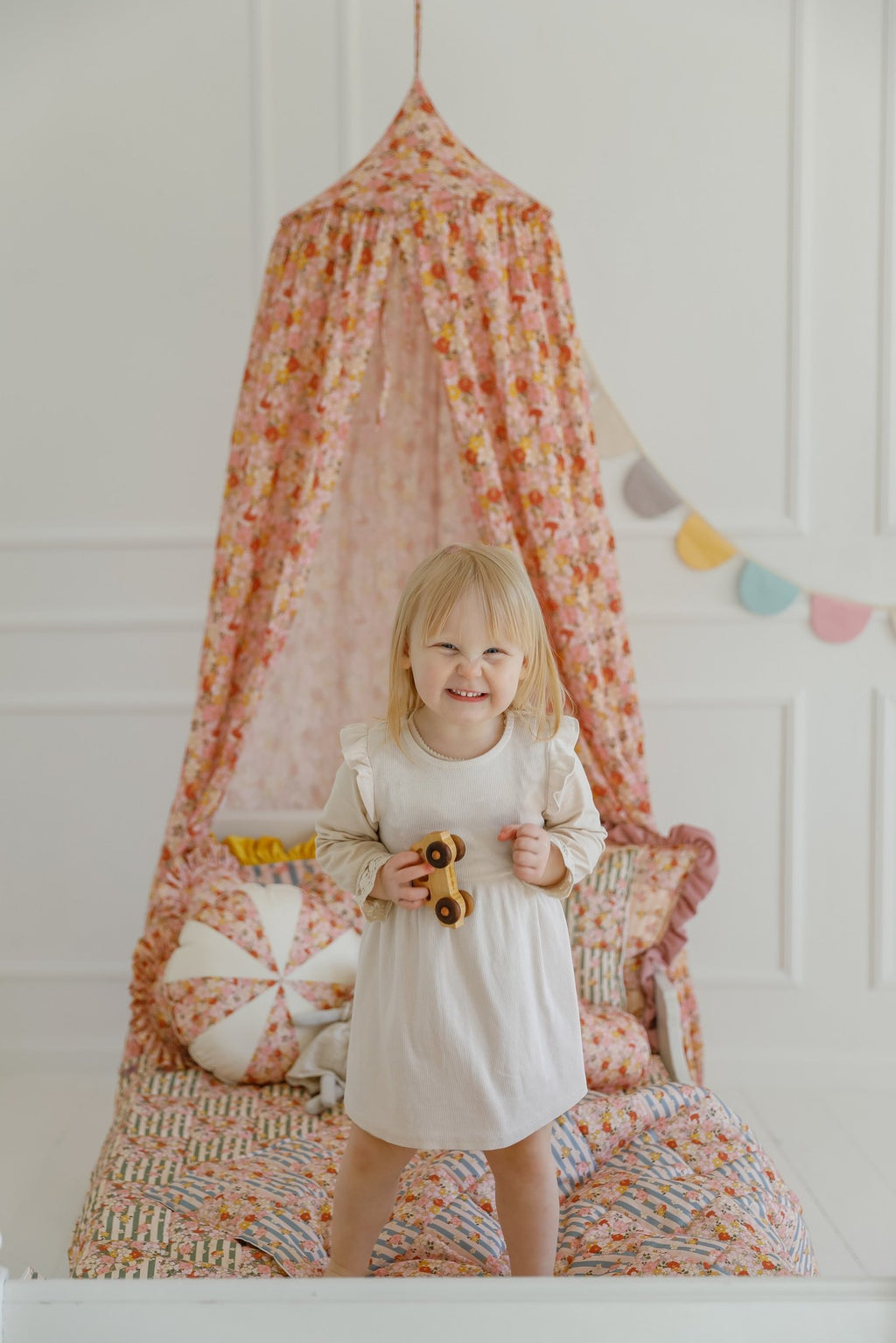 9. Girl standing under floral canopy with cushions and garland in a bright room