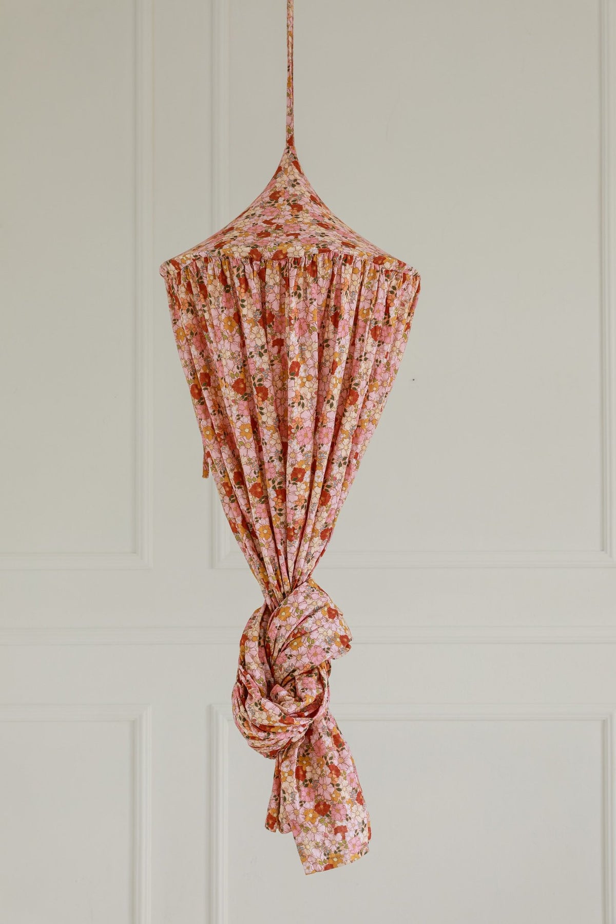 16. Floral canopy tied up in pink and orange hues against a plain wall