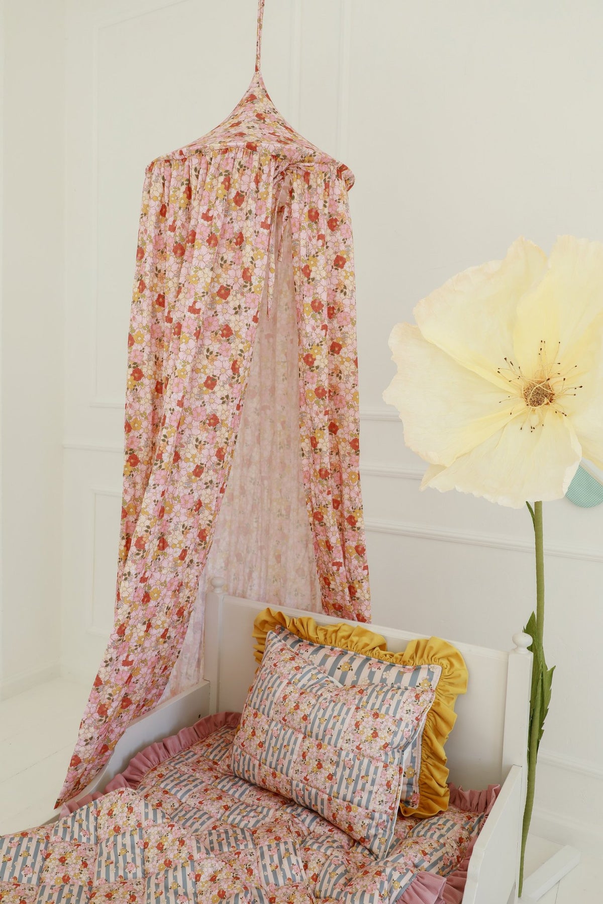 1. Child's bed with floral canopy in pink and orange hues, featuring matching pillow and flower decor in a bright room