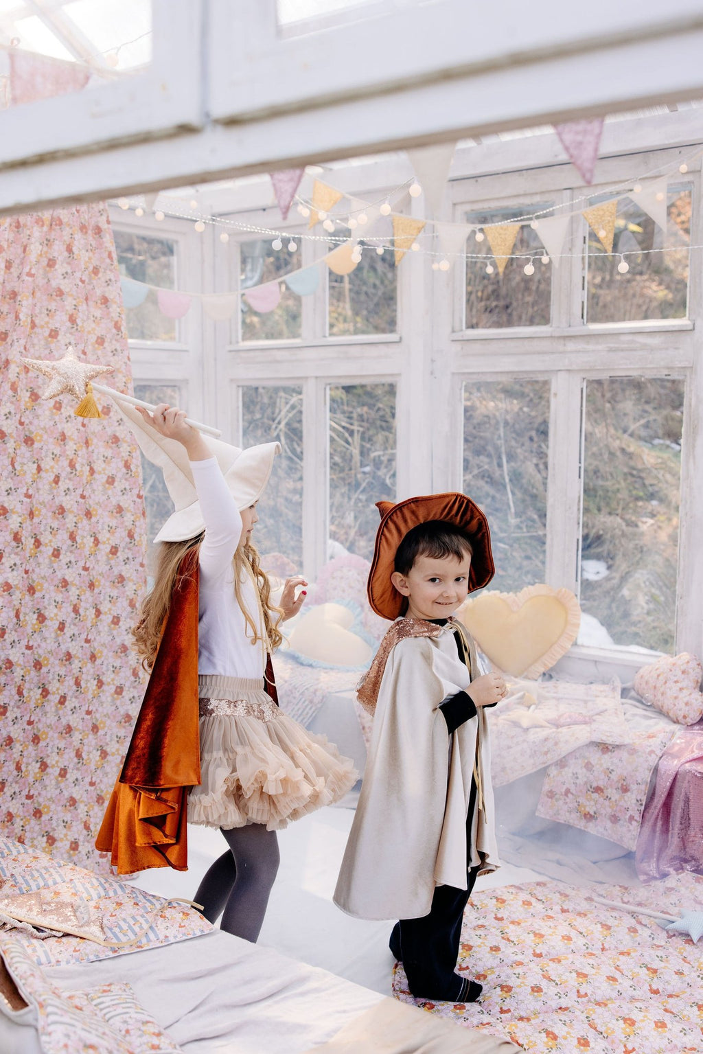 7. Two children in costumes near floral canopy in a bright playroom