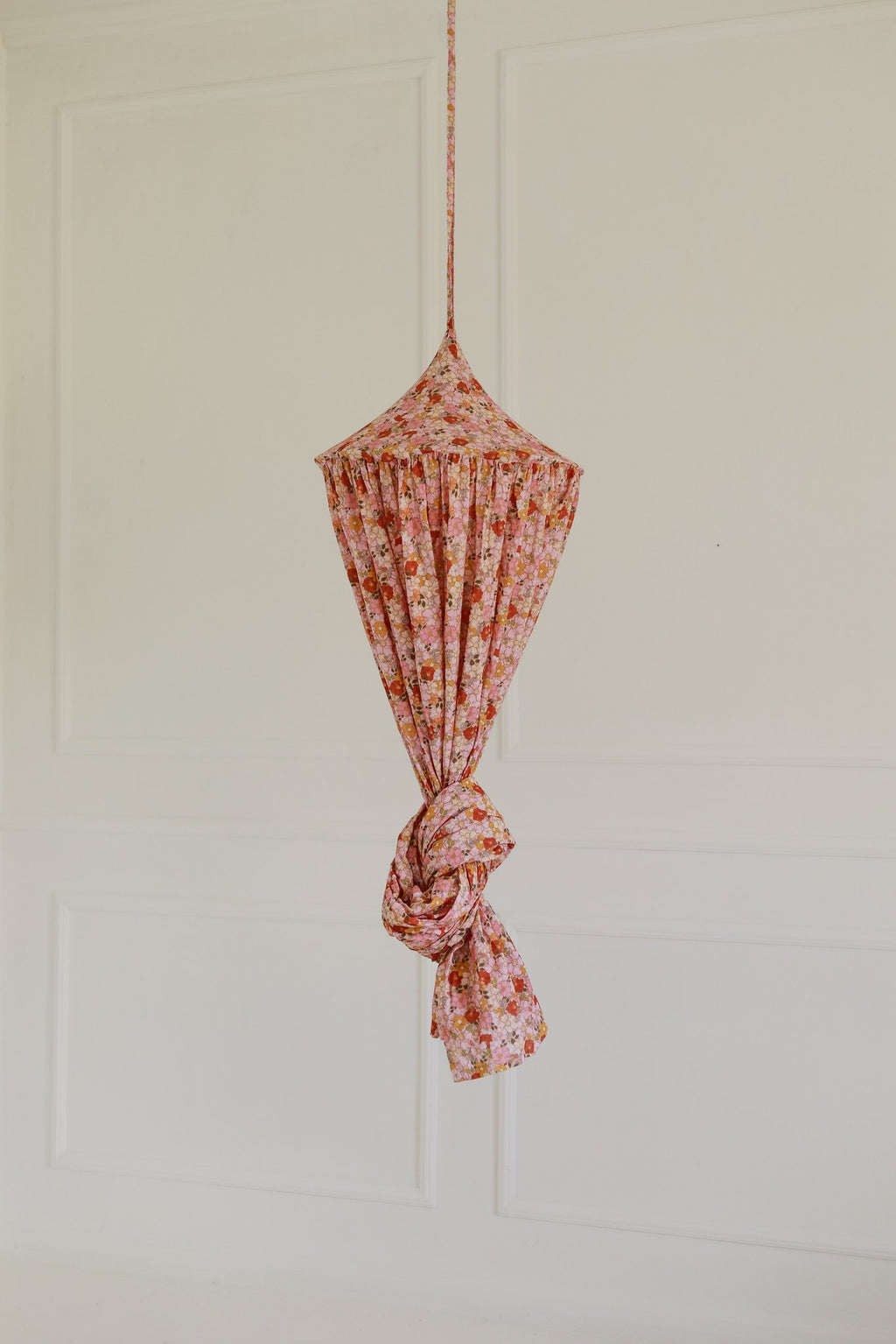 15. Floral canopy tied up in pink and orange hues against a plain wall