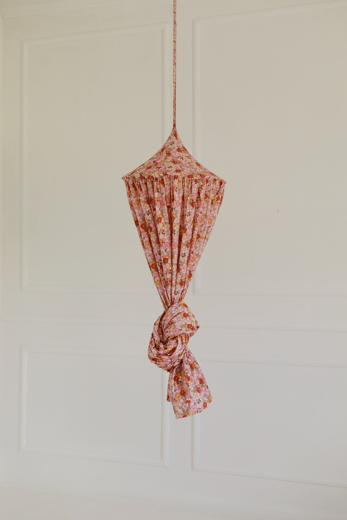 15. Floral canopy tied up in pink and orange hues against a plain wall