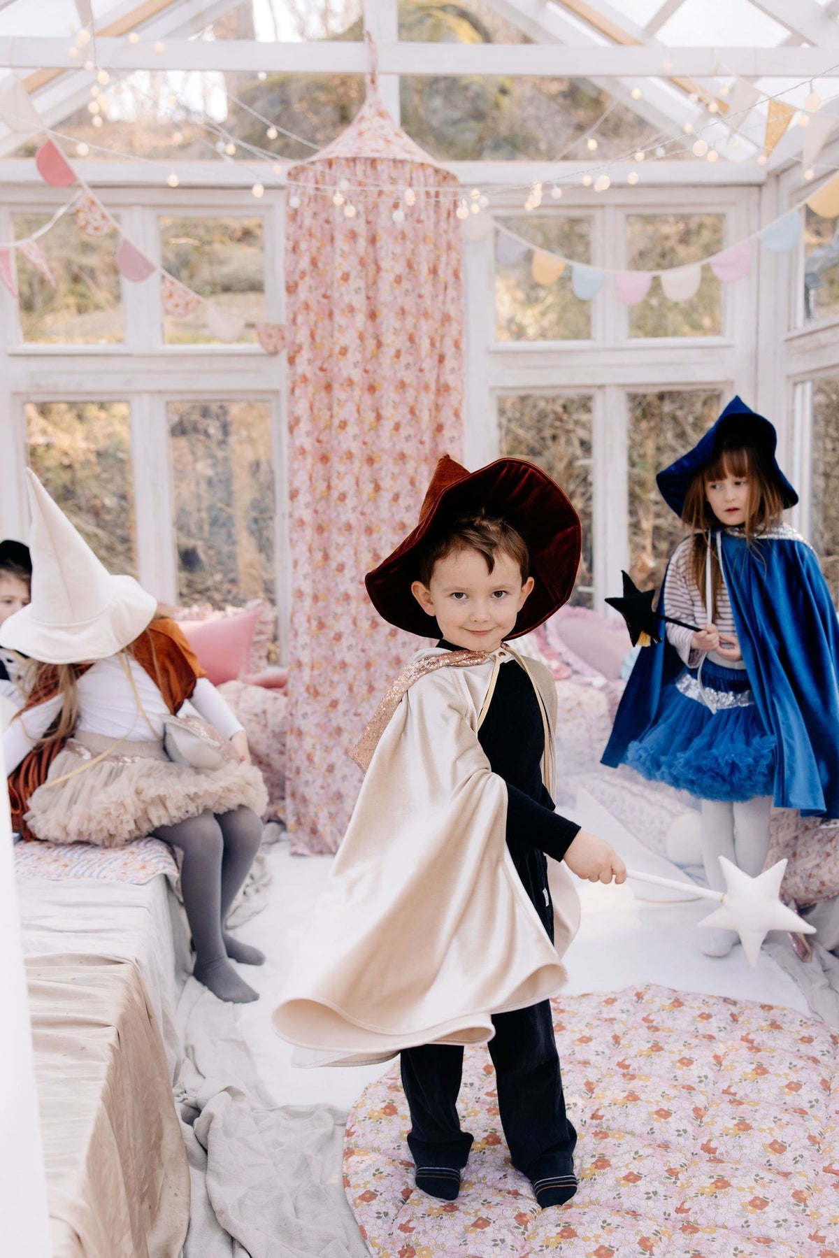 5. Children in costumes playing near floral canopy in a bright playroom