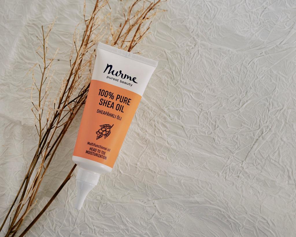 4. Flat lay of Nurme 100% Pure Shea Oil twist cap tube with dried plants on textured surface